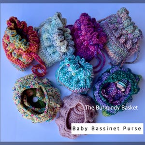 May include: A collection of handmade crochet baby bassinet purses in various colors, including pink, purple, blue, and yellow. Each purse has a drawstring closure and a ruffled edge. The text "Baby Bassinet Purse" is visible.