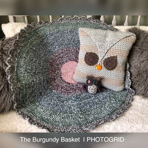 May include: A crocheted owl pillow with a striped pattern in beige, brown, and white. The pillow is sitting on a round, crocheted rug with a gradient of green, gray, and pink. The rug has a scalloped edge.