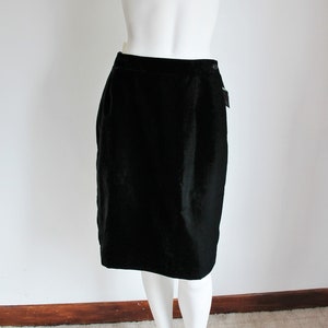 May include: A black velvet skirt on a white mannequin. The skirt is knee-length and has a straight silhouette.