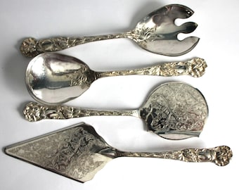 May include: A set of four silver serving utensils. The set includes a salad fork, serving spoon, pie server, and a serving spoon. Each piece has a floral design on the handle and a decorative pattern on the serving surface.