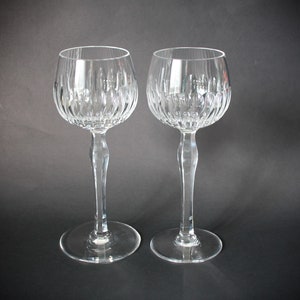 Peut inclure: Deux verres à vin en cristal transparent avec un motif texturé détaillé sur le bol et une longue tige élégante. Les verres ont une base ronde et sont posés sur un fond sombre, mettant en valeur leur design complexe.