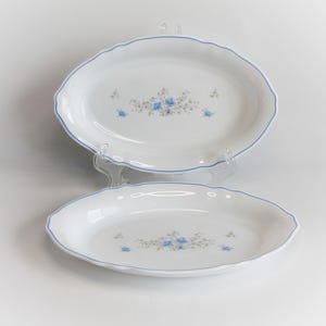May include: Two white oval serving dishes with a blue floral design and a blue trim.