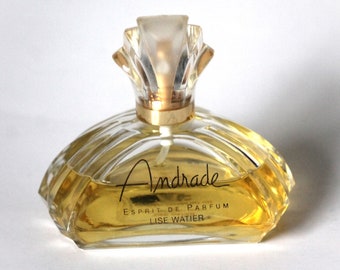 May include: A clear glass bottle of Andrade perfume with a gold cap and a gold label that reads "Esprit de Parfum Lise Watier".