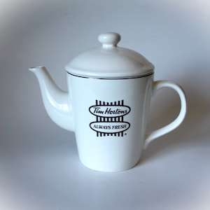 Puede incluir: Tetera de cerámica blanca con un logotipo negro de Tim Hortons y las palabras "Siempre fresco".
