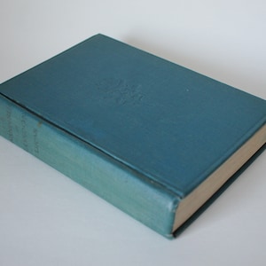 May include: A teal-coloured hardcover book with embossed detailing on the cover. The book's spine displays the title and author's name in gold lettering. The pages are aged, and the book appears to be vintage.