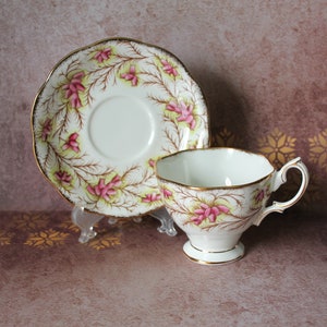 Può includere: Servizio da tè bianco con motivo floreale rosa e bordi dorati. Il piattino e la tazza hanno un bordo smerlato. La tazza ha una base a piedistallo e un manico curvo. Ideale per servire il tè.