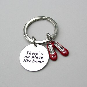 May include: Silver keychain with a round charm that says "There's no place like home" and two red ruby slipper charms.