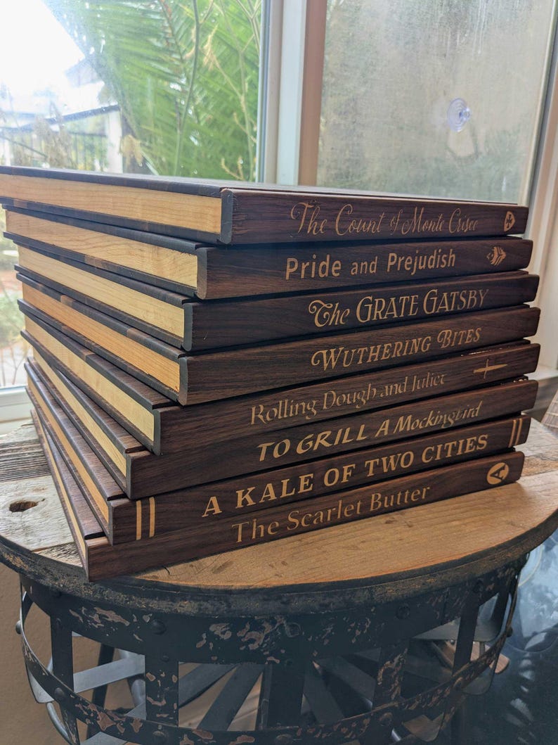 A stack of book shaped cutting boards shows the detail work on the Maple inlay pages and the inlay titles on the spine.