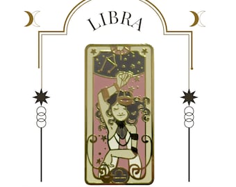 May include: Gold-tone enamel pin featuring a pink and white illustration of a woman holding a scale, with the word "LIBRA" above the image.