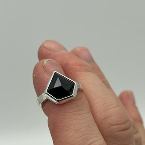 Peut inclure: Une bague en argent avec une pierre précieuse noire de forme géométrique.