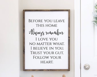 May include: A framed wooden sign with the text "BEFORE YOU LEAVE THIS HOME Always remember I LOVE YOU NO MATTER WHAT. I BELIEVE IN YOU. TRUST YOUR GUT. FOLLOW YOUR HEART." The sign is hanging on a white wall.