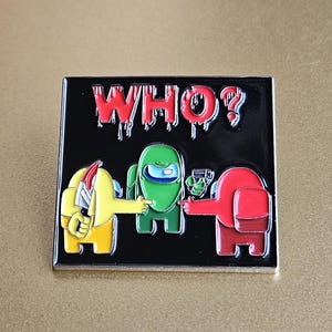 May include: A black enamel pin with a red, green, and yellow Among Us character design. The pin features the text "WHO?" in red dripping letters.