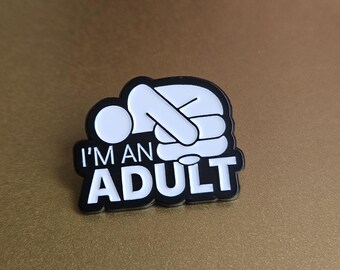 May include: Black and white enamel pin with a stick figure slumped over and the text "I'm an Adult".