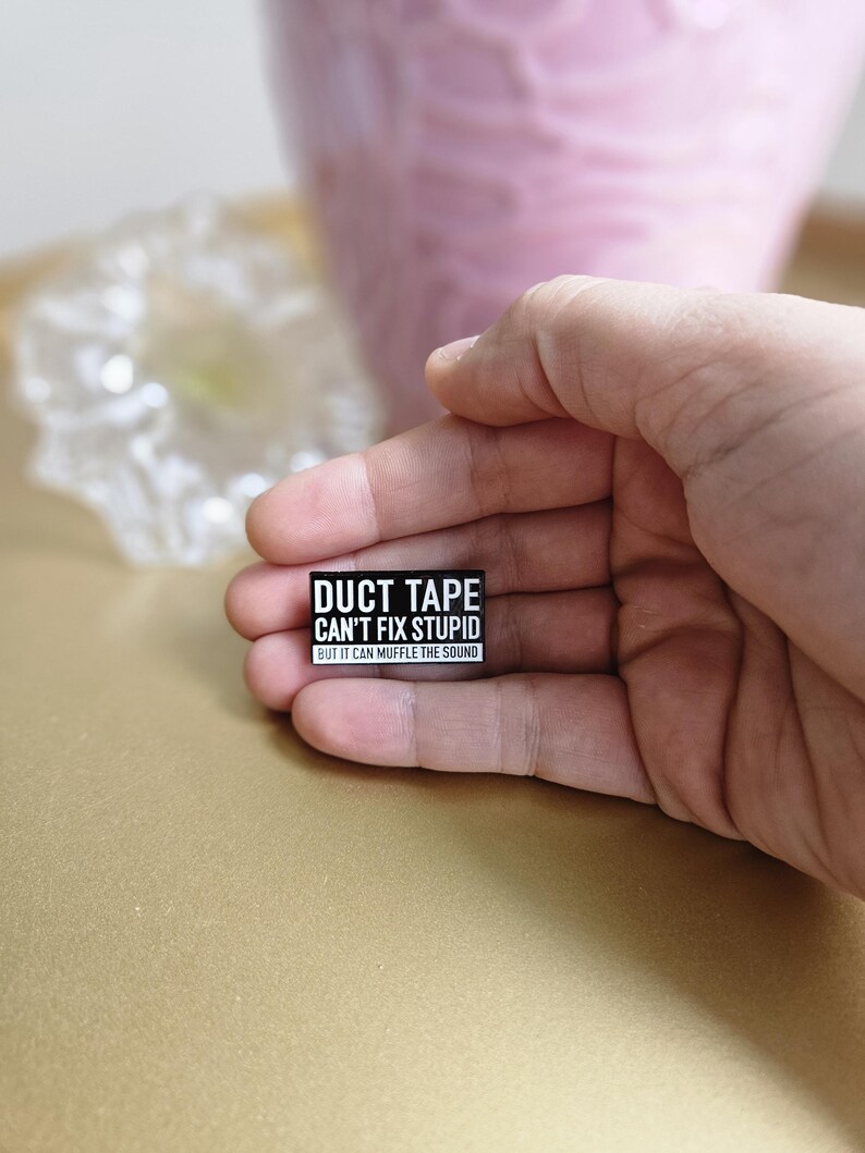 May include: Black and white sticker with the text "Duct Tape Can't Fix Stupid But It Can Muffle The Sound".