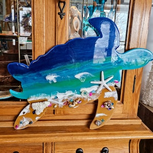 May include: A blue, green, and white resin sea turtle wall decor with a beach scene and seashells.