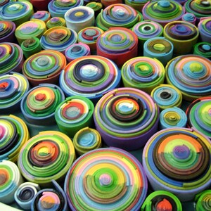 Puede incluir: Primer plano de una obra de arte circular y colorida hecha de anillos conc&eacute;ntricos apilados de papel. Los anillos est&aacute;n dispuestos en un patr&oacute;n aleatorio, creando una superficie visualmente atractiva y texturizada.