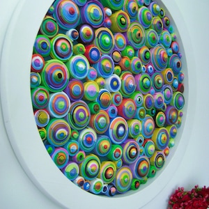 Puede incluir: Una pieza de arte de pared circular hecha de c&iacute;rculos conc&eacute;ntricos coloridos. Los c&iacute;rculos est&aacute;n dispuestos en un patr&oacute;n aleatorio y est&aacute;n pintados en varios tonos de verde, azul, amarillo, rosa y morado.
