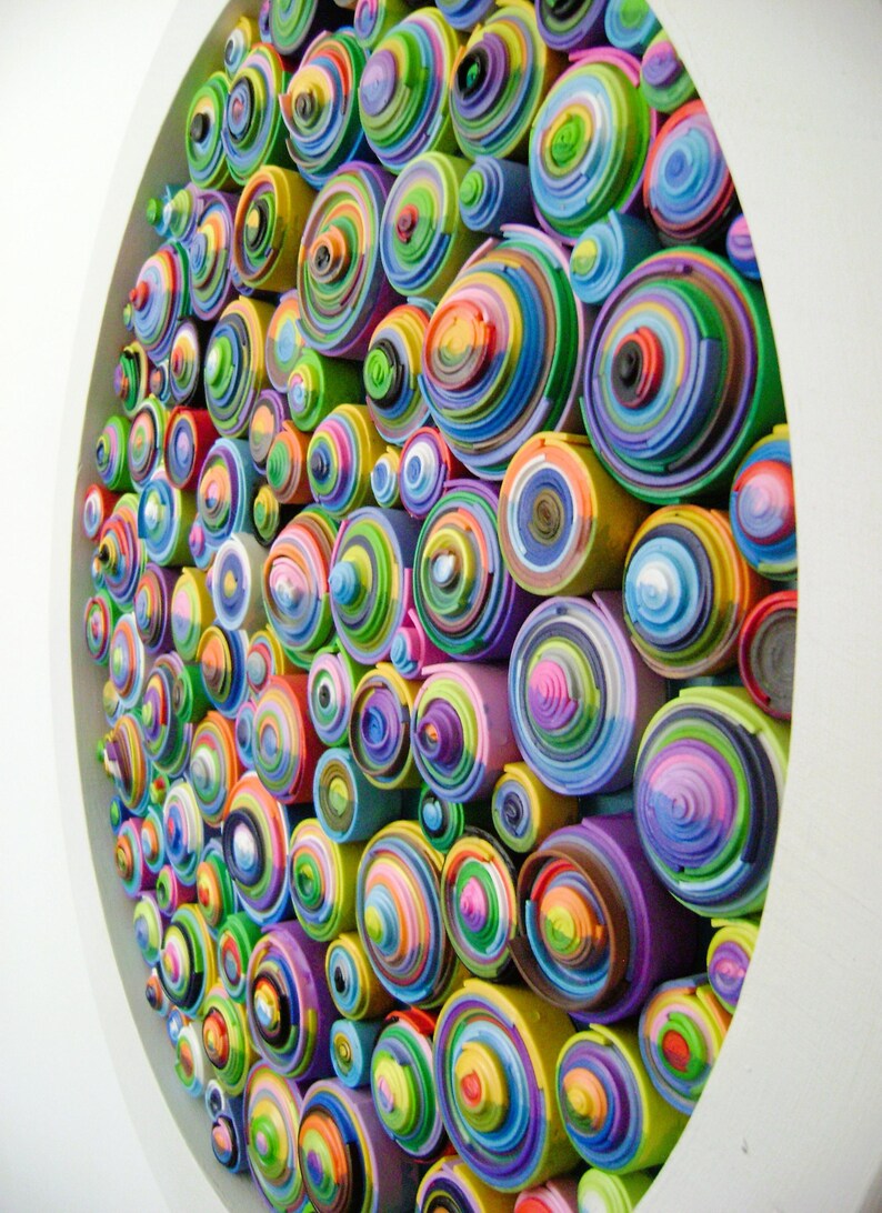 Puede incluir: Una pieza de arte de pared circular hecha de c&iacute;rculos conc&eacute;ntricos de papel de colores. Los c&iacute;rculos est&aacute;n dispuestos en un patr&oacute;n aleatorio, creando un dise&ntilde;o abstracto y visualmente estimulante.