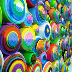 Puede incluir: Una pieza de arte de pared hecha de c&iacute;rculos conc&eacute;ntricos coloridos. Los c&iacute;rculos est&aacute;n hechos de papel o cart&oacute;n enrollado y est&aacute;n pintados en varios tonos de azul, verde, amarillo, rojo y morado.
