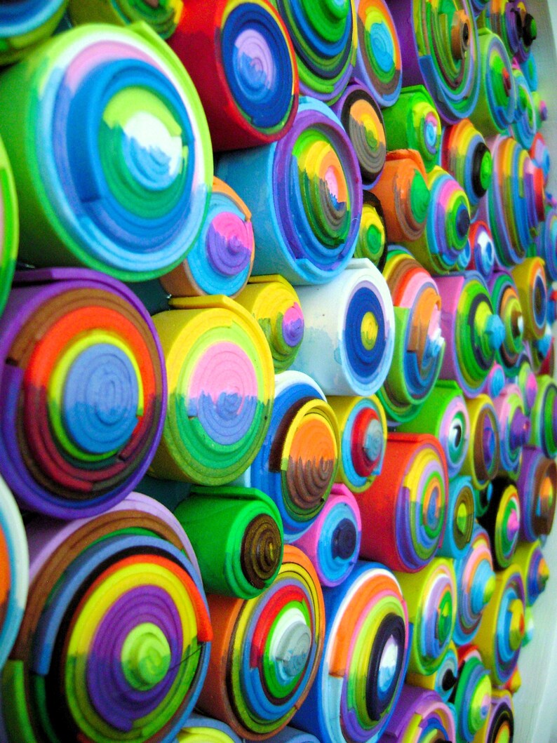 Puede incluir: Una pieza de arte de pared hecha de c&iacute;rculos conc&eacute;ntricos coloridos. Los c&iacute;rculos est&aacute;n hechos de papel o cart&oacute;n enrollado y est&aacute;n pintados en varios tonos de azul, verde, amarillo, rojo y morado.
