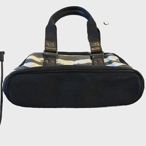 Puede incluir: Bolso de mano a rayas blancas y negras con asas y base negras. El bolso tiene forma rectangular con la parte inferior redondeada. Las asas est&aacute;n sujetas con herrajes met&aacute;licos y detalles de cuero.