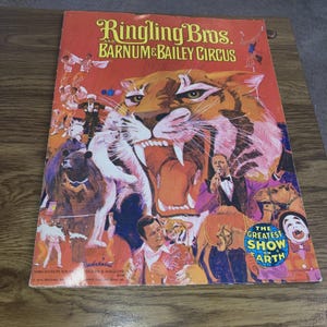 May include: A vintage Ringling Bros. and Barnum & Bailey Circus program and magazine cover. The cover features a roaring tiger, circus performers, and the text "The Greatest Show on Earth."