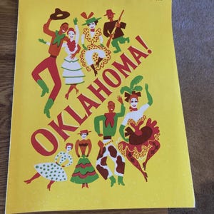 May include: A vintage poster with a yellow background and the word "OKLAHOMA!" in large red letters. The poster features stylized illustrations of people in colourful costumes, dancing and celebrating. The date "4/17/55" is written in the upper right corner.