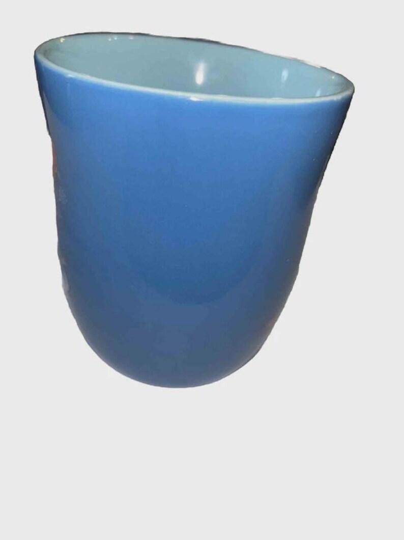 May include: A blue ceramic vase with a curved, asymmetrical shape. The exterior is a solid, glossy blue, while the interior has a lighter blue hue. The vase has a smooth, polished finish.