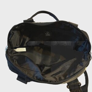 Puede incluir: Bolso tote negro y gris con asa superior y cierre de cremallera. El bolso tiene un interior espacioso y una peque&ntilde;a etiqueta en el interior. El bolso parece estar hecho de un material duradero y tiene forma rectangular.