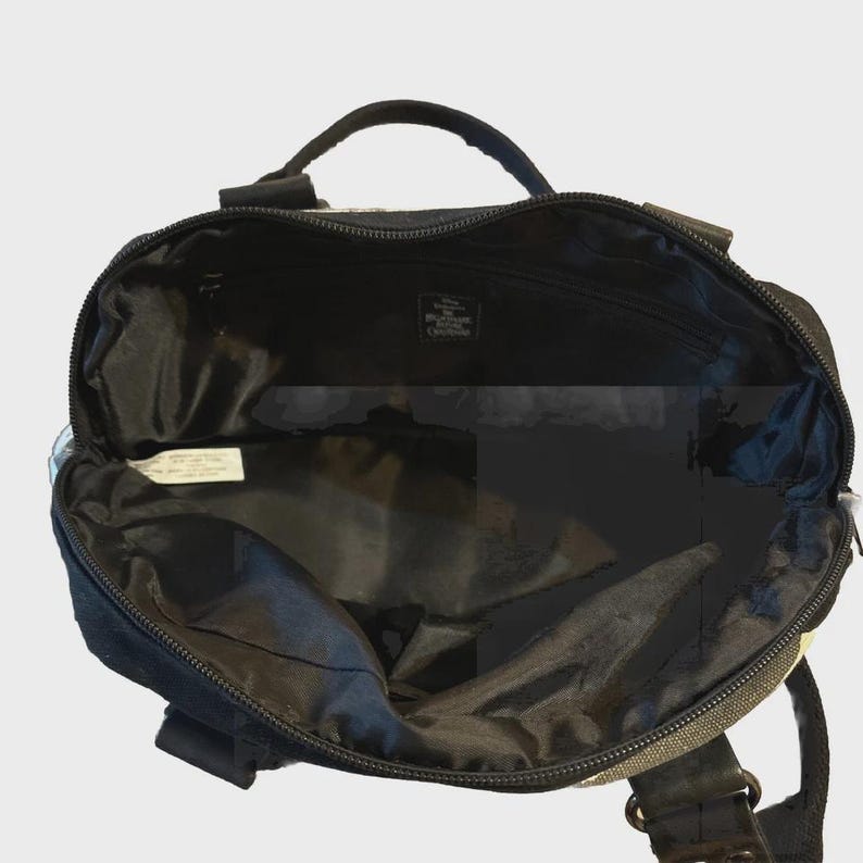 Puede incluir: Bolso tote negro y gris con asa superior y cierre de cremallera. El bolso tiene un interior espacioso y una peque&ntilde;a etiqueta en el interior. El bolso parece estar hecho de un material duradero y tiene forma rectangular.