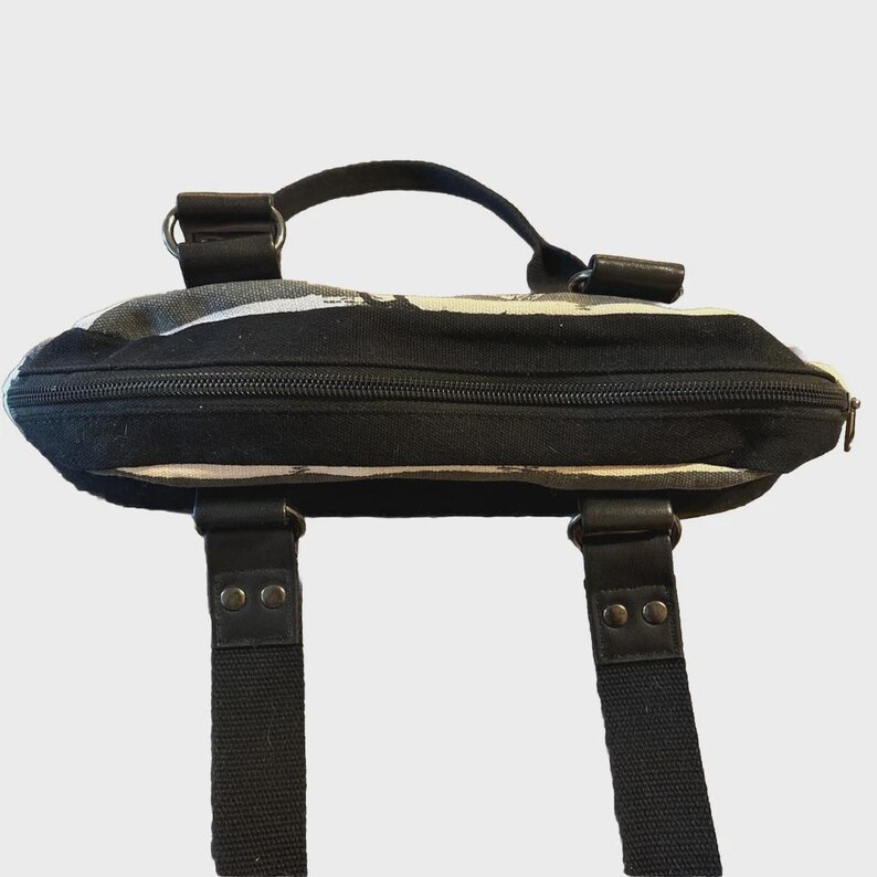 Puede incluir: Bolso tote con estampado en blanco y negro con asa superior y dos correas para el hombro. El bolso tiene cierre de cremallera y detalles de cuero. El dise&ntilde;o presenta un patr&oacute;n abstracto en blanco y negro.