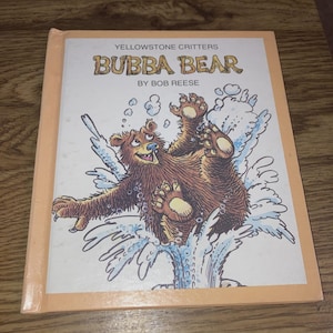 May include: A children's book titled "Bubba Bear" by Bob Reese. The cover features a cartoon illustration of a brown bear splashing in water. The book has a light orange border and the text "Yellowstone Critters" at the top.
