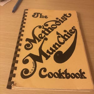 May include: A spiral-bound cookbook titled "The Methodist Munchies Cookbook" with black lettering on a tan cover. The title is in a decorative font. The author's name, A.P. Guard, is printed at the bottom left.