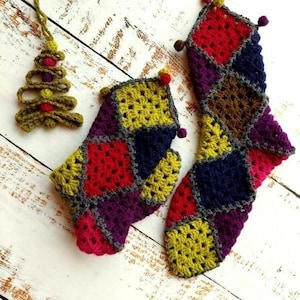 May include: A handmade Christmas stocking and matching mitten, crocheted with a patchwork design in vibrant colors including red, yellow, purple, and blue. A small crocheted Christmas tree ornament is also present, adding to the festive theme.