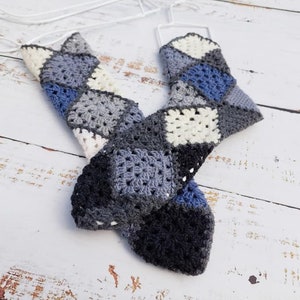 Könnte beinhalten: Ein gehäkelter Schal in den Farben Blau, Grau und Weiß mit einem Granny-Square-Muster.