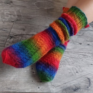 Peut inclure: Une paire de chaussettes rayées arc-en-ciel avec un motif en tricot torsadé. Les chaussettes sont faites d'un fil doux et coloré.