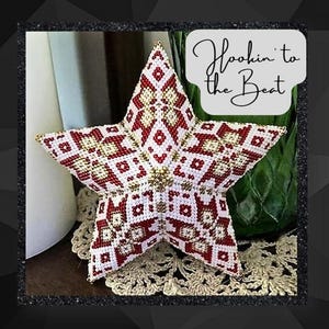 May include: A red, white, and gold beaded star ornament with a geometric pattern. The star is sitting on a crocheted doily. The text "Hookin' to the Beat" is written in black cursive on a white background.