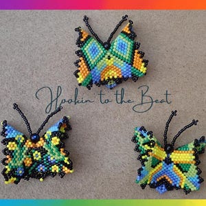 May include: Three beaded butterfly brooches in shades of blue, green, yellow, and orange. The butterflies are all the same size and shape, but each has a different color pattern. The text "Hookin' to the Beat" is written in cursive below the butterflies.