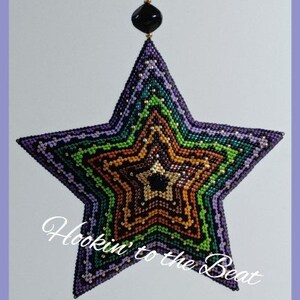 May include: A multi-colored beaded star ornament with a black bead at the top. The star is made of a variety of colors, including purple, green, brown, and black. The text "Hookin' to the Beat" is written in white on a black background below the star.