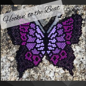 May include: A purple and black beaded butterfly with the text "Hookin' to the Beat" above it.