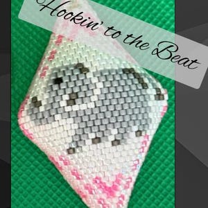 Op de afbeelding: Een handgemaakte, diamantvormige kralen hanger. Het patroon bestaat uit witte, grijze, roze en zwarte kralen. De tekst "Hookin' to the Beat" staat over de afbeelding.