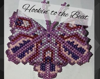 May include: A purple, pink and white beaded butterfly with the text "Hookin' to the Beat" above it.