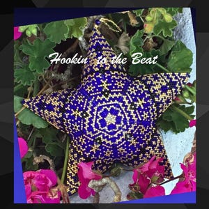 May include: A blue and gold star-shaped ornament with a geometric pattern. The ornament is surrounded by green leaves and pink flowers. The text "Hookin' to the Beat" is visible in the image.