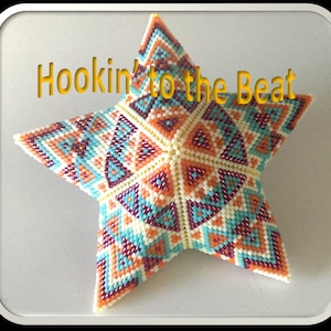 Op de afbeelding: Een kleurrijk stervormig kralen ornament met een geometrisch patroon in tinten oranje, turquoise, wit en paars. Het ornament heeft de tekst "Hookin' to the Beat" erop.