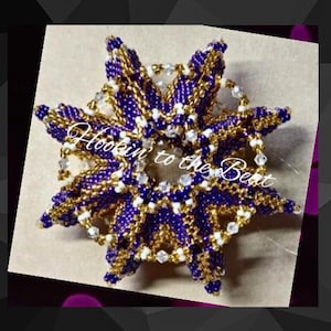 以下が含まれることがあります： 白と透明なクリスタルの中心を持つ、紫と金のビーズでできたスターバースト。スターバーストは透明なクリスタルのリングで囲まれています。テキスト「Hookin' to the Beat」は黒地に白で書かれています。