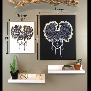 Puede incluir: Dos pinturas de lienzo en blanco y negro con detalles dorados que representan a una mujer con un peinado afro. La pintura m&aacute;s grande tiene 40,6 cm de ancho y 50,8 cm de alto. La pintura m&aacute;s peque&ntilde;a tiene 27,9 cm de ancho y 35,6 cm de alto. Las pinturas est&aacute;n colgadas en una pared con estantes blancos debajo.