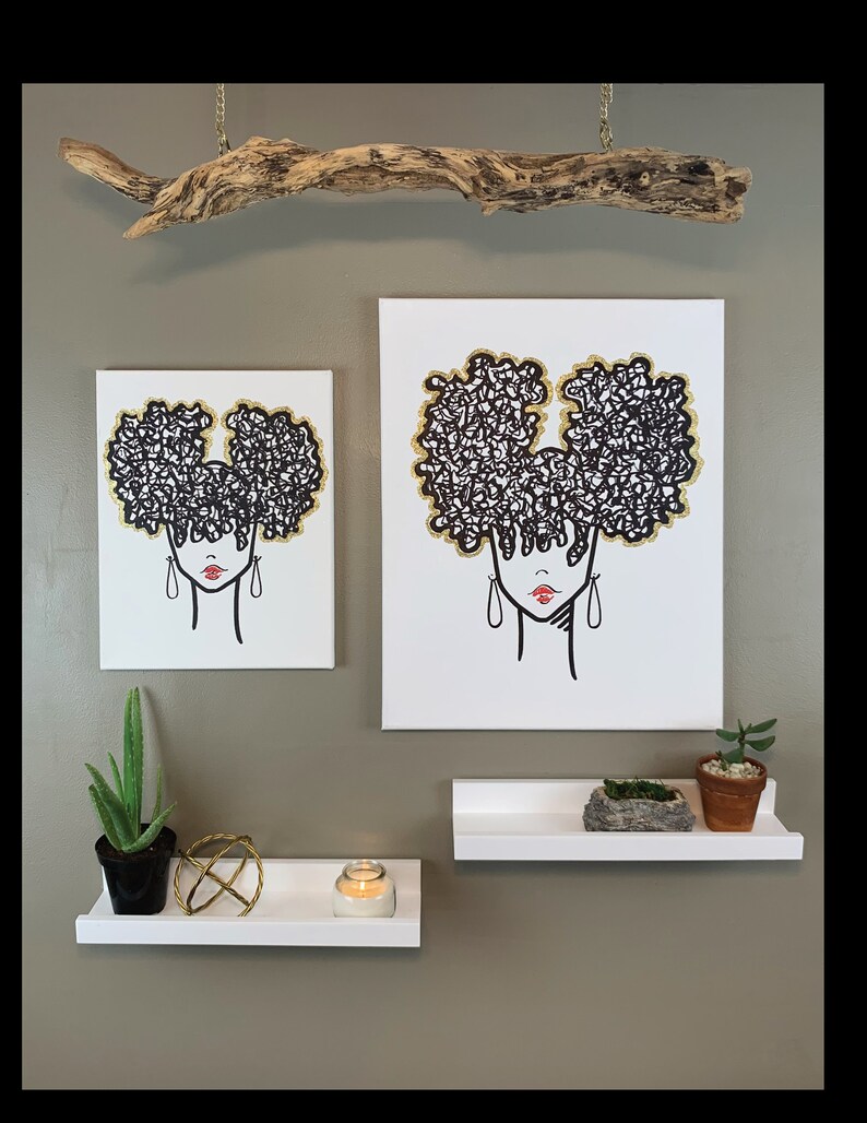 Puede incluir: Dos impresiones en lienzo en blanco y negro de una mujer con un peinado afro. Las impresiones est&aacute;n colgadas en una pared con una rama de madera flotante encima. Hay dos estantes blancos debajo de las impresiones, uno con una vela y una esfera decorativa, y el otro con una peque&ntilde;a planta en maceta y una roca.