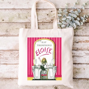 May include: A white canvas tote bag with a pink and white striped design. The bag features a book cover illustration of a girl writing on a mirror with the text "KAY THOMPSON'S ELOISE" in yellow.