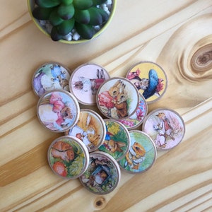 May include: Twelve wooden round discs with colorful illustrations of rabbits and other animals. The discs are decorated with floral patterns and have a rustic, vintage aesthetic.
