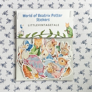 May include: A sheet of stickers featuring characters from Beatrix Potter's stories. The stickers include Peter Rabbit, Jemima Puddle-Duck, Squirrel Nutkin, and more. The stickers are printed on white paper and have a glossy finish. The sheet is packaged in a clear plastic bag with a header card that reads "World of Beatrix Potter Stickers" and "LITTLEVINTAGETALE".